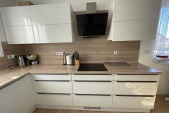 Detail bílé kuchyně s dřevěnou deskou